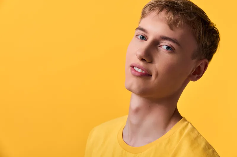 Yellow background, yellow shirt, smiling man in casual style, bright color with studio lighting for fashion, lifestyle and product showcase in a clean modern setting.
