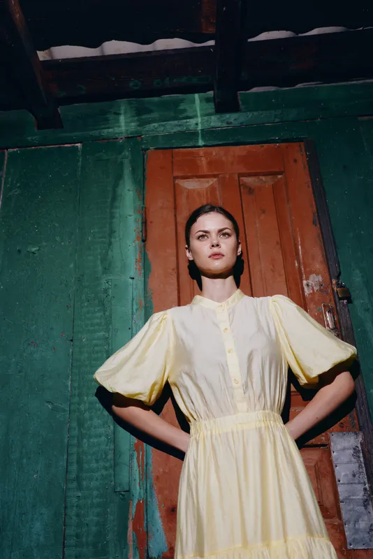 Woman portrait in yellow vintage dress doorway, authentic inclusivity