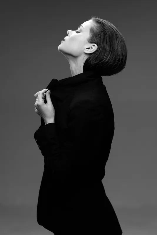 Black and white portrait of a thoughtful woman in a dark jacket with closed eyes and upward face