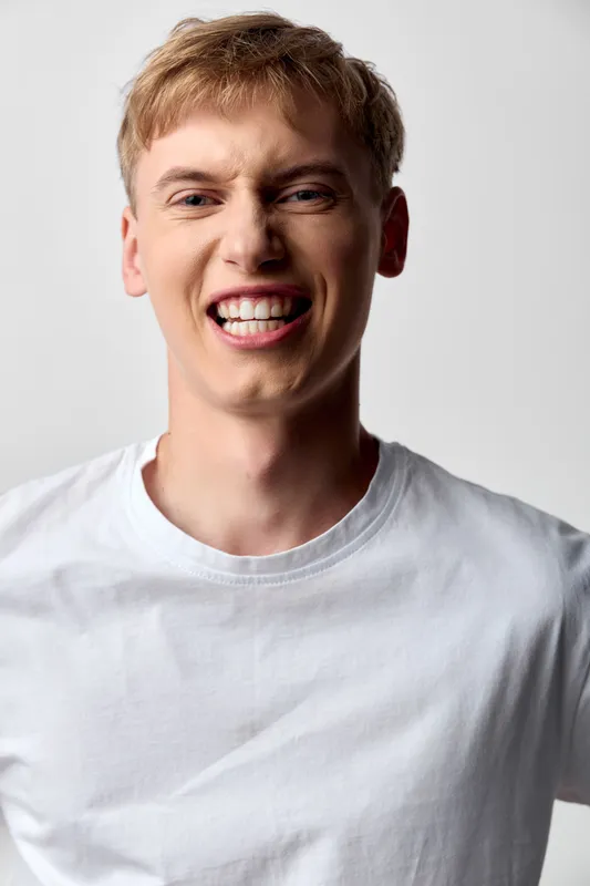 Smiling man wearing a white t shirt in a studio, conveying friendly confidence, approachable vibe and versatile appeal for lifestyle or marketing visuals