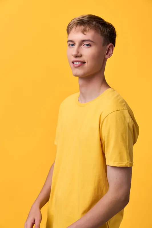 Yellow themed studio shot of a smiling man in a yellow t shirt, standing against a vivid yellow background, casual pose, clean lighting, cheerful mood, simple fashion image without branding