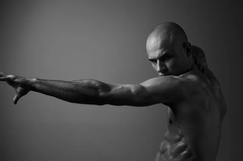 Powerful man posing in black and white, showcasing strength and determination in a dramatic fashion. His intense expression captures the essence of focused energy.