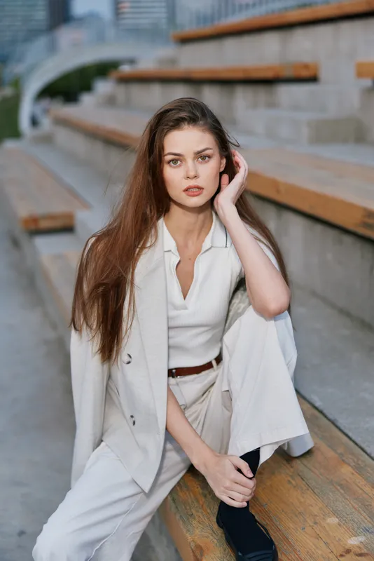 woman in white business suit sitting on wooden stairs outdoors with serious expression natural light autumn fashion clothing