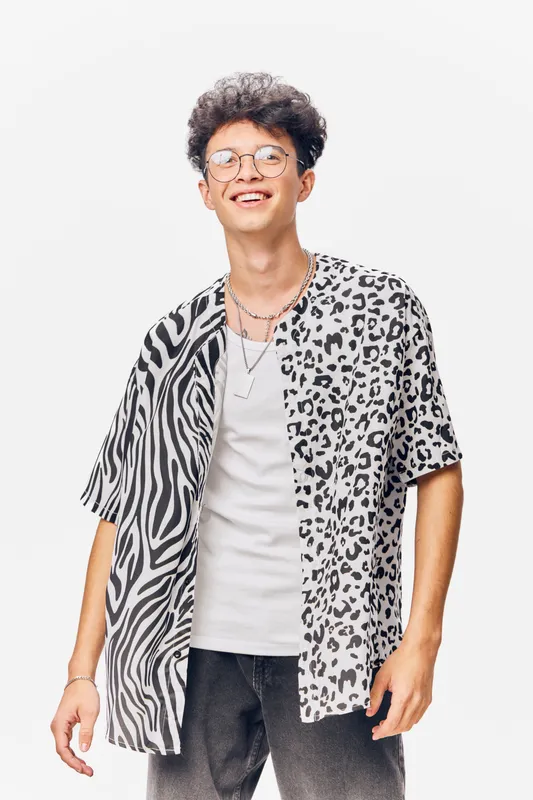 young man smiling wearing patterned black and white shirt with glasses, casual style, isolated on white background, happiness and modern fashion