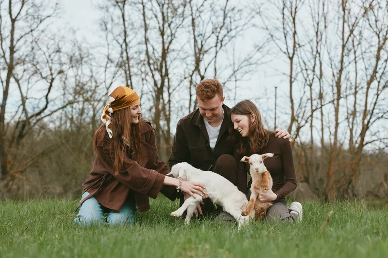 Goat kid family outdoor lifestyle in a field and meadow with smiles, showing animal companionship in a warm farm setting. A candid moment of care, joy, and togetherness.