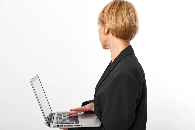 Person profile, laptop typing in a bright studio with white background, technology work focus, remote communication concept, calm confident mood during office routine