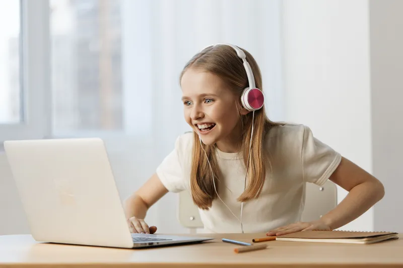 Happy young girl with headphones enjoying online learning at home, bright room, positive emotions, educational concept, modern style, indoor setting