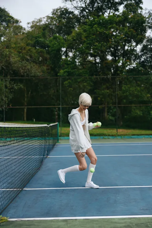 Young female tennis player practicing on a lush green court, showcasing athletic wear and determination, surrounded by vibrant nature in summer