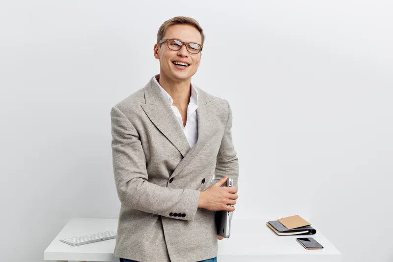 smiling man working with laptop white modern office casual blazer glasses digital nomad concept