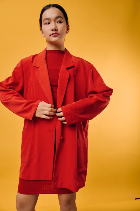 Young woman wearing red jacket and dress posing on yellow background, fashion style with confident look and casual outfit for modern trendy clothing concept.
