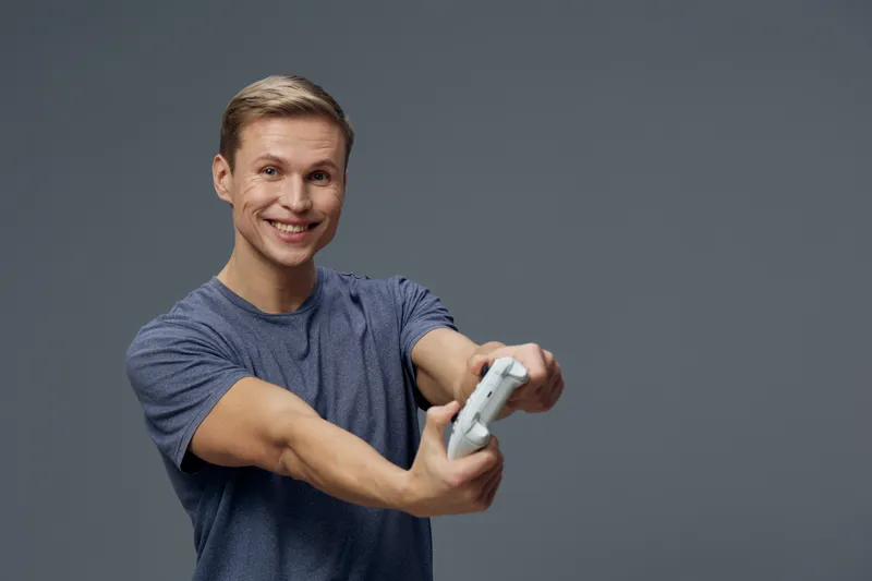 Smiling young man wearing casual blue t-shirt taking selfie with smartphone isolated on plain gray background studio portrait. People lifestyle concept
