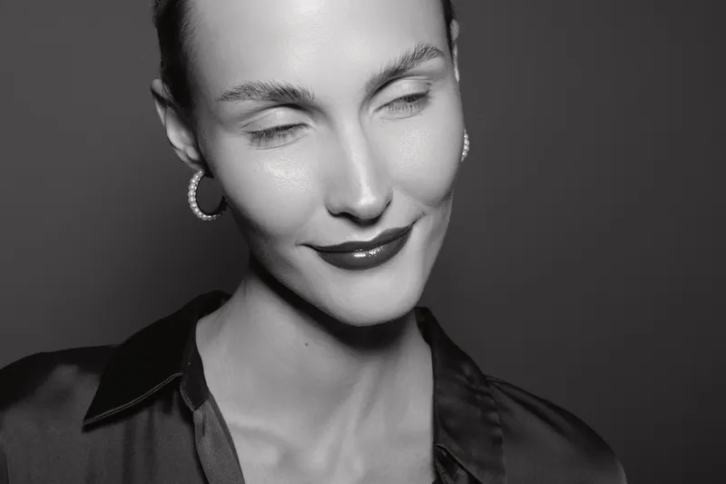 Closeup of a smiling white woman with light skin and short hair in black blouse on dark background. Concept of emotion, beauty, and female portrait.