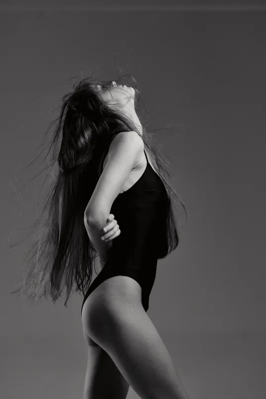 Black and white woman posing in bodysuit with long hair and expressive posture