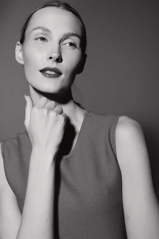 Portrait of a young white woman with fair skin posing confidently, wearing sleeveless top. Studio lighting highlights her natural beauty and elegant facial features.