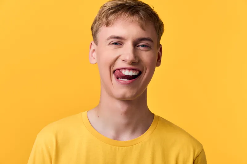 Smiling man wearing yellow shirt against a bright yellow background, showcasing cheerful expression and sunny mood, clean studio setup, casual vibe, positive energy for lifestyle and wellness themes
