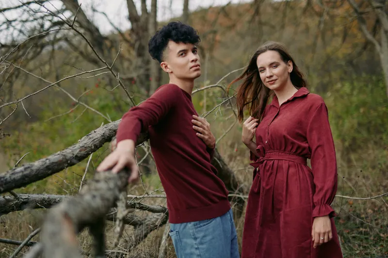 A candid portrait captures authenticity through a relaxed pose and natural lighting as two figures stand by a weathered fence, conveying credibility and calm in autumn tones.