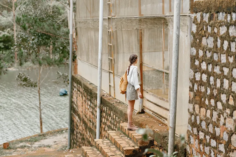 Young woman contemplating by the riverside, wearing a casual outfit, expressing serene emotions, surrounded by nature, reflecting on a peaceful retreat