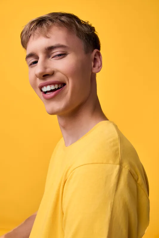 Smiling man in a bright yellow shirt against a vivid yellow background, a cheerful casual vibe perfect for lifestyle, positivity, and energetic branding visuals