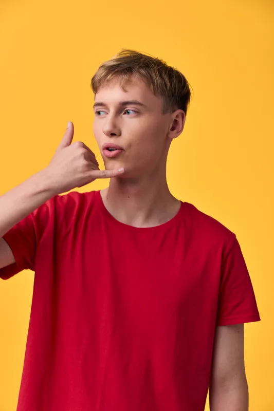 Man, hand gesture shaka sign with red t shirt against yellow background, casual attitude and playful vibe, modern expression and friendly energy, studio shot