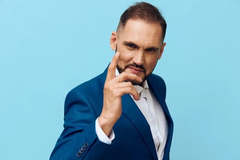 A confident business professional man stands against a vivid blue background, exuding focus and determination, inviting the viewer to sense leadership and strategic thinking.