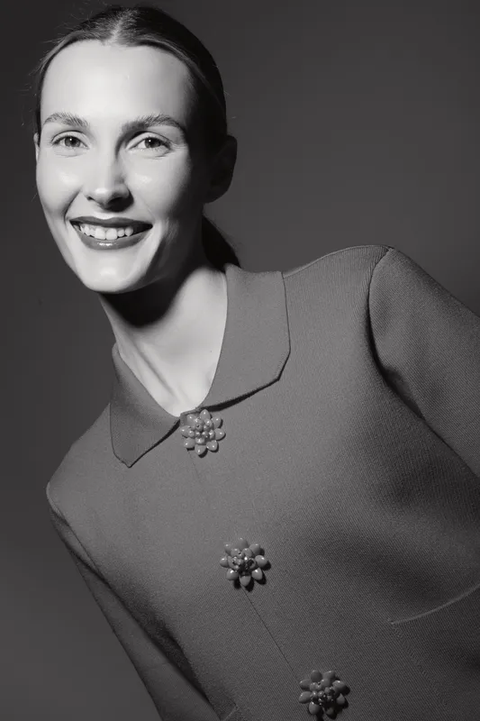 Smiling white woman with pale skin wears vintage textured dress with decorative buttons in black and white portrait. Classic fashion concept.