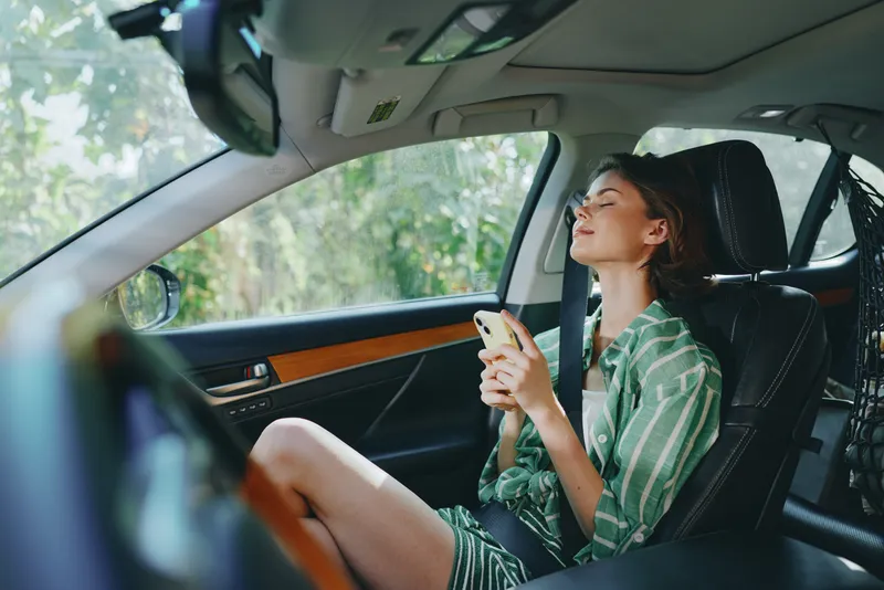 Car, driver, woman, smile a cheerful woman sits in the car seat with eyes closed and a relaxed smile, basking in calm daylight, comfortable and ready for a journey ahead.