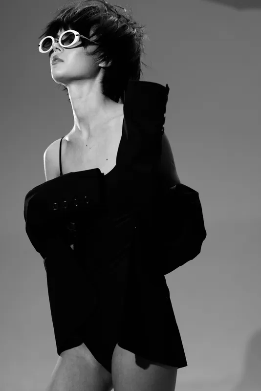 Black and white stylish woman wearing sunglasses and a jacket, posing confidently with modern fashion and attitude.