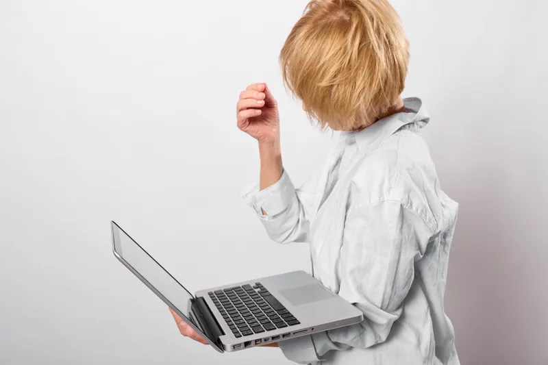 Back view of child using laptop computer, small hands on keyboard, focused learning moment, screen facing forward, modern technology and education concept in studio for kids