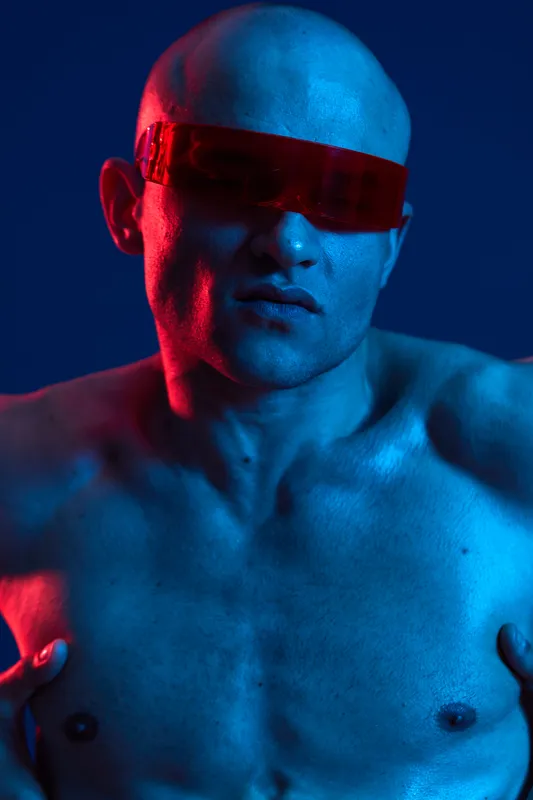 A striking man with futuristic sunglasses featuring a blue and red neon glow, showcasing a unique artistic style that emphasizes modernity and individuality.