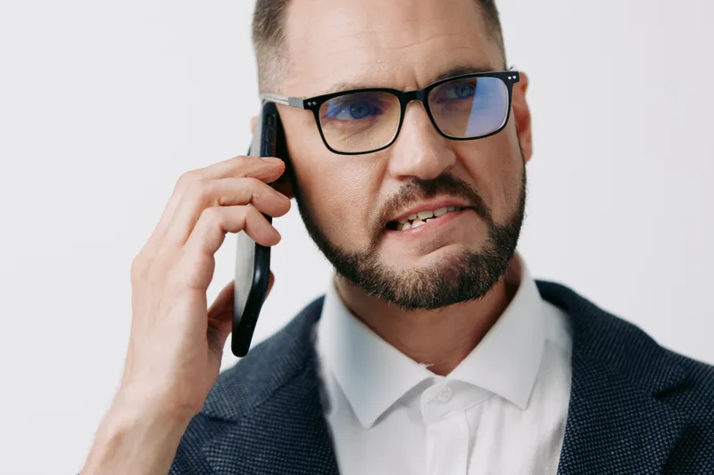 Professional businessman on a phone, displaying a determined emotion, captured against an isolated colorful background for a bold business portfolio and messaging.