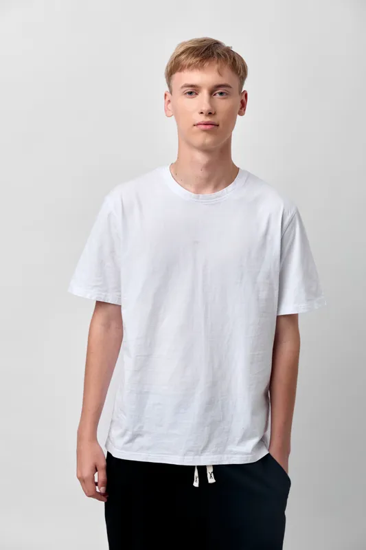 White t shirt on a relaxed man model in a clean studio, showcasing casual fashion for everyday wear, minimalist style, soft lighting, plain background, front pose, versatile basic apparel