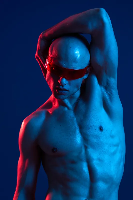 Striking portrait of a man wearing sunglasses, showcasing dramatic lighting in blue and red hues for a bold, modern aesthetic.