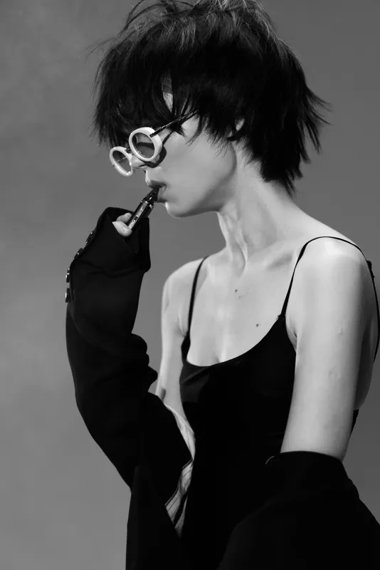 Black and white portrait of a stylish woman with short hair wearing sunglasses smoking a pipe