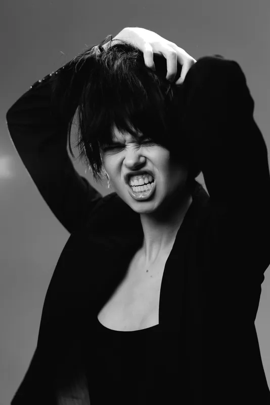 Black and white portrait of a frustrated woman with short hair expressing strong emotion and tension.