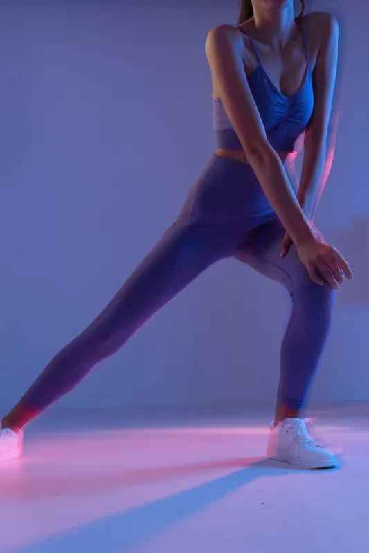 woman sport fitness stretching in purple activewear, indoors with colorful lighting, focused on leg workout and balance, dynamic and healthy lifestyle concept