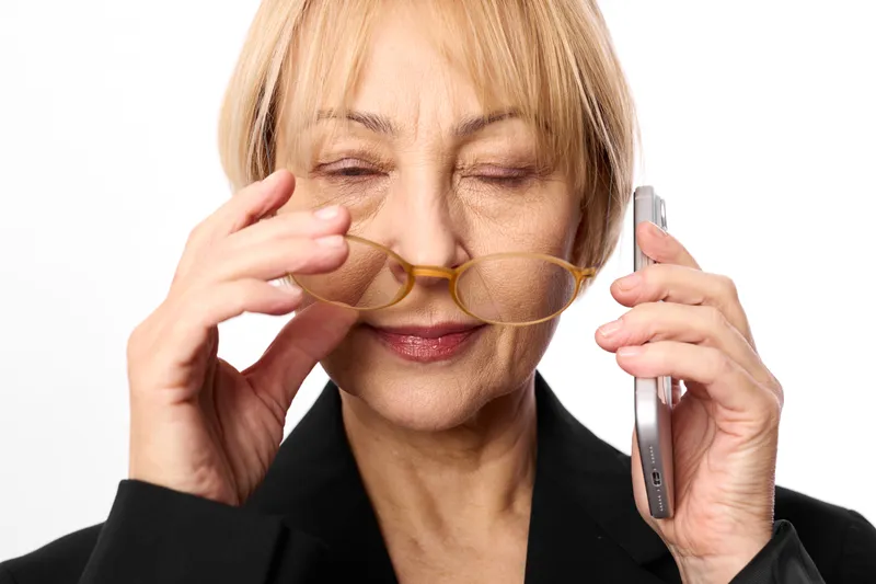 Tired businesswoman wearing a blindfold holds a smartphone to her ear and adjusts her hands, eyes closed, concept of stress, uncertainty, and blocked vision