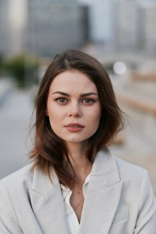 Confident business woman in professional attire, with a serene expression against a modern urban background, embodies strength and elegance in the workplace.