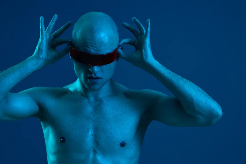 A focused man adjusts his futuristic headset, showcasing technology and innovation in a captivating blue-toned environment. Ideal for tech and sci-fi themes.