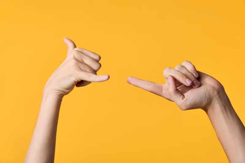 Hands framing a creative scene with fingers forming a rectangle against a bright orange background, closeup gesture highlighting playful design and visual composition