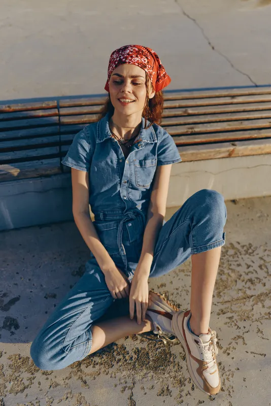 lifestyle woman in modern boho-western denim street style sitting casually outdoors with film color tone and relaxed expression under natural light