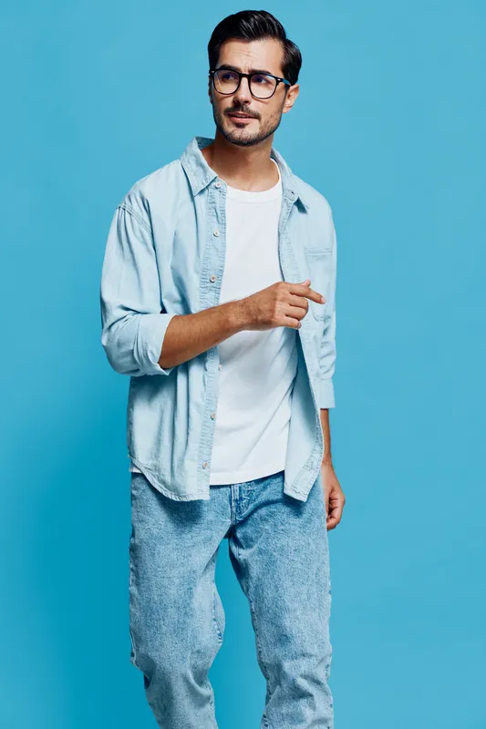 Full body stylish young caucasian man wear blue shirt glasses look confident towards the camera isolated on bright solid blue background studio portrait. Fashion concept