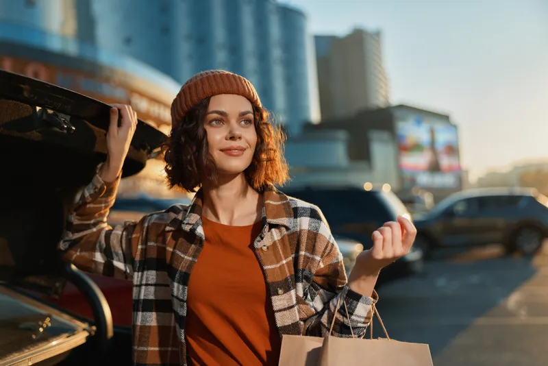 Woman shopping by car trunk in urban street at golden hour, candid portrait and lifestyle moment showing authenticity, mindful living and emotional storytelling with warm glow.