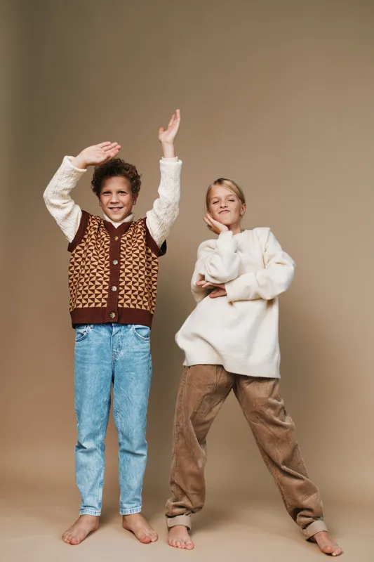 Authentic lifestyle portrait of two kids in playful school themed setting, showcasing candid energy and creative expression in a natural studio shoot.