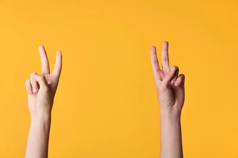 Peace sign, two hands in a victory gesture against a bold orange background, conveying positive energy, simple composition and casual vibe for motivational, social media, or lifestyle campaigns