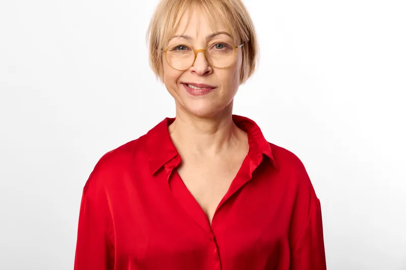 Woman portrait senior glasses smile, red blouse on white background, closeup headshot of friendly mature woman, relaxed cheerful expression in studio light