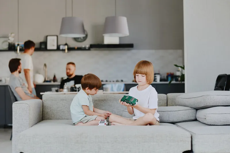 Two children playing with toys in a modern living room, showcasing a warm family atmosphere and joyful interaction in a stylish environment.