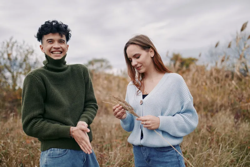 Authentic moment in a natural field captures two people sharing a candid exchange, showcasing real expression and simple style that convey credibility and warmth.