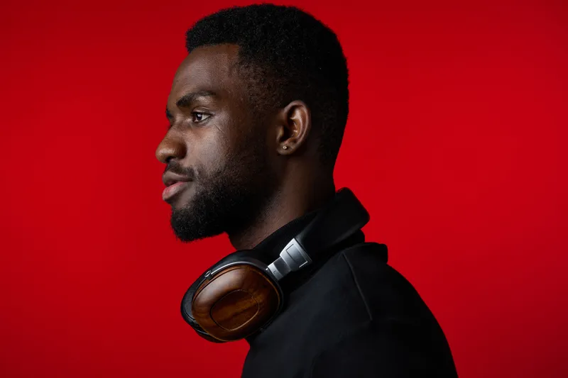 Portrait of a young black man with headphones, showcasing a profile against a bold red background, expressing confidence and modern style for music enthusiasts