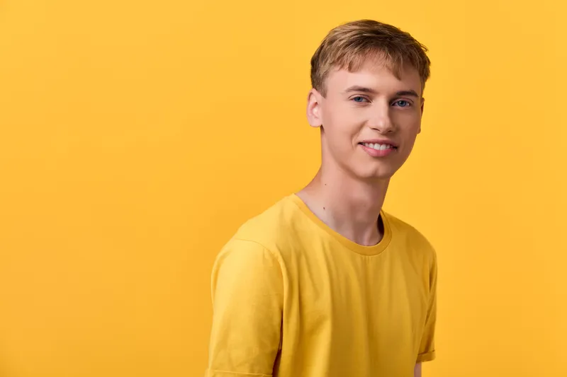 Young man in a yellow shirt stands against a vivid yellow background, casual style, bright mood, clean composition suitable for lifestyle, fashion, and product showcase projects