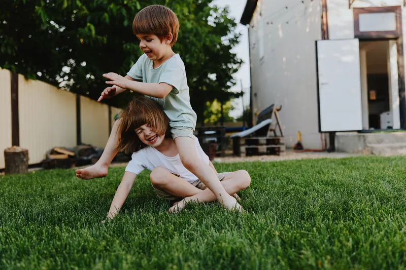 Happy children playing together on green grass, filled with joy and laughter, showcasing a carefree summer day, capturing the essence of childhood fun.